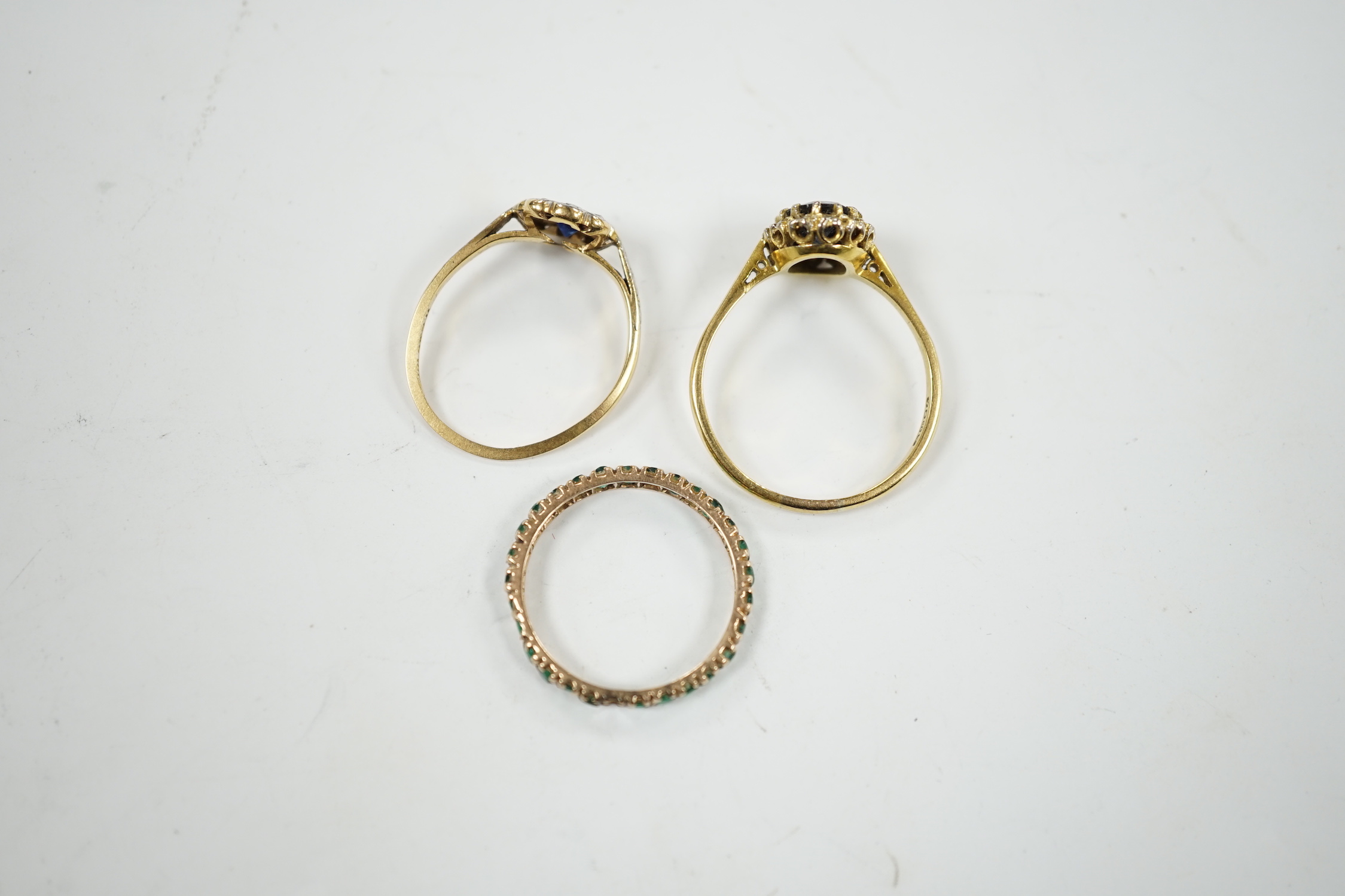 A 1920's 18ct and plat, sapphire and diamond set flower head cluster ring, size L, a 1960's 18ct gold sapphire and diamond set oval cluster ring and a yellow metal and emerald chip set full eternity ring, gross weight 6.